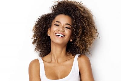 Young woman with big, curly hair shows off her big, bright smile